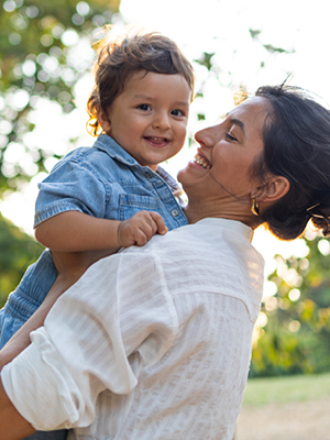 A smiling mom holding her son outside