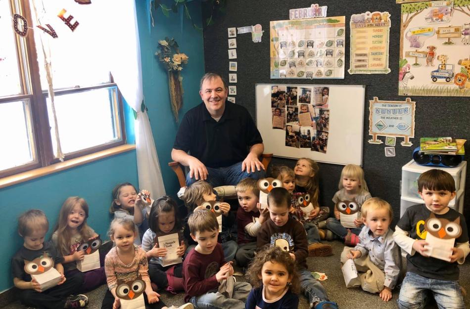 man reading to a bunch of kids