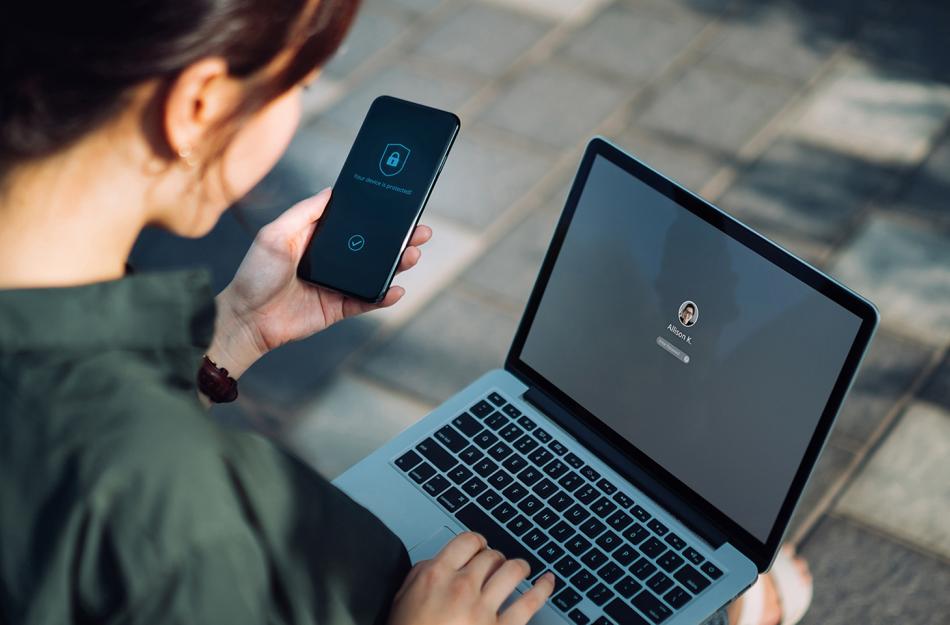 woman holding a phone while working at her laptop